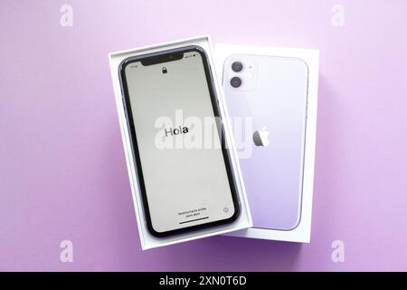 Moskau, Russland, Mai 2021: Neues iPhone 12 in violetter Farbe in offener Markenbox auf lilafarbenem Hintergrund. Auf dem iPhone-Bildschirm, willkommen auf Spanisch - Hola. Stockfoto