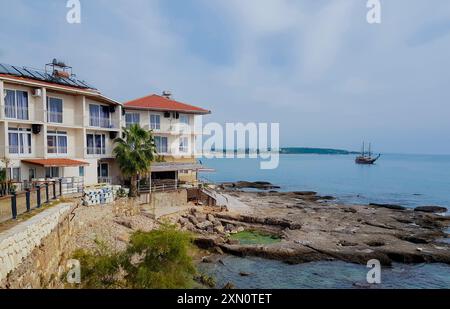 Side, Türkei, November 2019: Segelboot mit abgesenktem Mittelmeer segelt entlang einer Küste mit Apartmenthotel. Stockfoto