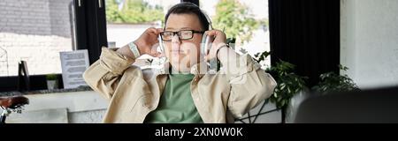 Ein junger Mann mit Down-Syndrom hört Musik mit Kopfhörern. Stockfoto