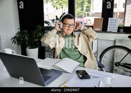 Ein junger Mann mit Down-Syndrom entspannt sich in seinem Büro mit Kopfhörern und genießt Musik. Stockfoto