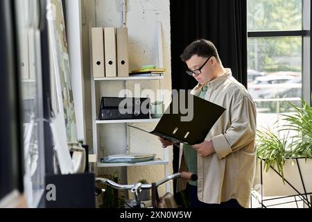 Ein junger Mann mit Down-Syndrom steht in der Nähe eines Bücherregals und überprüft Dokumente. Stockfoto