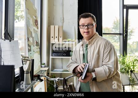 Ein junger Mann mit Down-Syndrom steht in einem hellen Raum mit einem Fahrrad und einem Gemälde an der Wand. Stockfoto