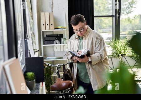 Ein junger Mann mit Down-Syndrom steht in der Nähe eines Fahrrads und liest Notizen in einem Buch. Stockfoto