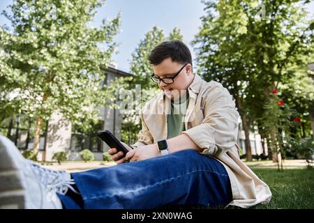 Ein Mann mit Down-Syndrom entspannt sich auf dem Gras und genießt einen Moment am Telefon. Stockfoto