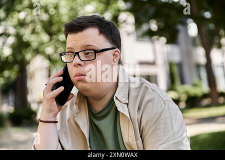 Ein Mann mit Down-Syndrom sitzt draußen und spricht am Telefon. Stockfoto