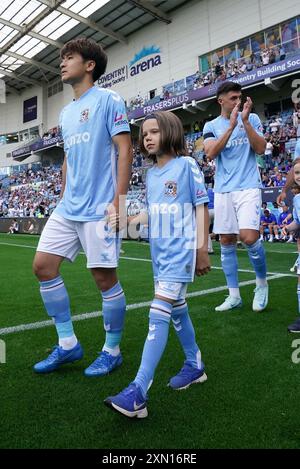 Tatsuhiro Sakamoto in Coventry City (links) und ein Maskottchen gehen vor dem Freundschaftsspiel vor der Saison in der Coventry Building Society Arena aus. Bilddatum: Dienstag, 30. Juli 2024. Stockfoto