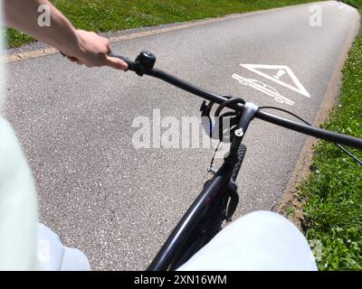 Arco, Trentino, Italien - 30. Juni 2024: Ein Radfahrer fährt auf einem Radweg, auf der Straße gibt es eine Warnung vor einer Kreuzungsstraße. Unfallgefahr auf einem Fahrrad Symbolbild *** ein Radfahrer fährt auf einem Radweg, auf der Straße befindet sich eine Warnung vor einer querenden Straße. Unfallgefahr auf dem Fahrrad Symbolbild Stockfoto