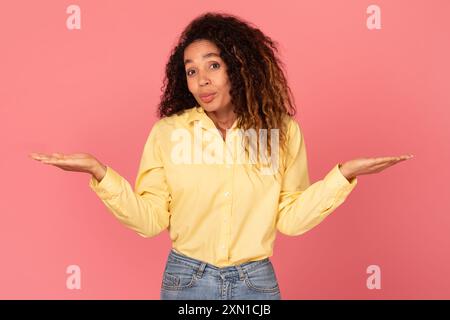 Junge Frau in gelbem Hemd, die mit Händen gegen Pink gestickt hat Stockfoto