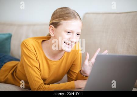 Teen Girl Video chatten auf Laptop, während sie auf der Couch liegen Stockfoto