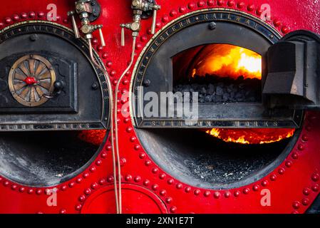 Nahaufnahme des Dampfkessels für den Crofton-Beam-Motor mit Kohleverbrennung im Inneren, mit den komplizierten Metallsteuerungen und der rot lackierten Struktur. Stockfoto