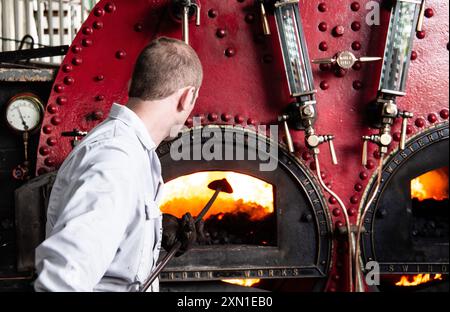 Ein Ingenieur überwacht und wartet die Kesselanlage mit einem glühenden Feuer im Kessel an der Crofton Beam Engine Canal Pumpstation. Stockfoto