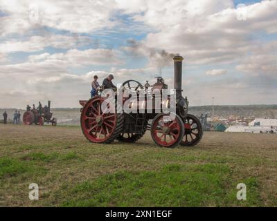 Eine historische Dampfmaschine fährt im Sommer auf einem hügeligen Feld mit einer Rauchwolke auf der großen dorset Dampfmesse in england Stockfoto