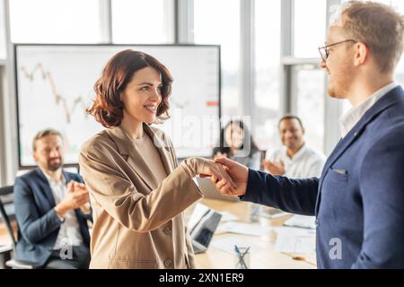 Geschäftsfrau schüttelt nach erfolgreicher Präsentation im Büro die Hand mit dem Kollegen Stockfoto