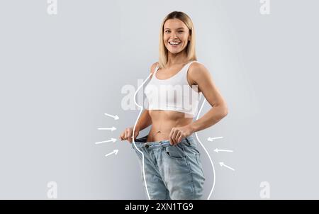 Fröhliche, schlanke blonde Frau in riesigen Jeans Stockfoto