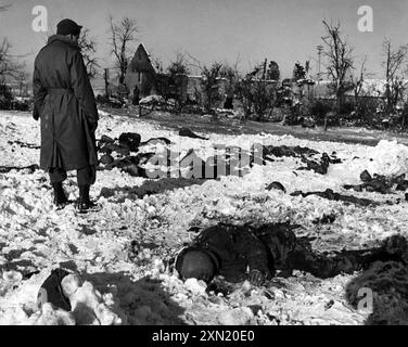 Ein US-Soldat beobachtet die Opfer des Massakers von Malmedy (17. Dezember 1944), bei dem 84 US-Kriegsgefangene von der Waffen-SS in Belgien, dem Zweiten Weltkrieg, ermordet wurden Stockfoto