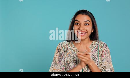 Fröhliche indianerin klatscht fröhlich an die Hände, ekstatisch über Leistungen. Aufgeregter Mensch, der auf gute Nachrichten reagiert, jubelt, applaudiert, isoliert über Studiohintergrund, Kamera B Stockfoto