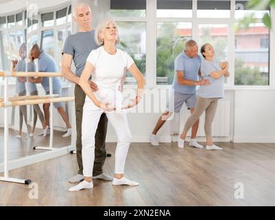 Reife Frau übt Plie-Position zu zweit mit Mann im Tanzstudio Stockfoto