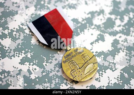 KIEW, UKRAINE - Medaille der US-Armee der Besatzung am 10. JULI 2024. US-Militärmedaille mit Band und Stift. Handgemachte Papierkopffiguren aus nächster Nähe Stockfoto