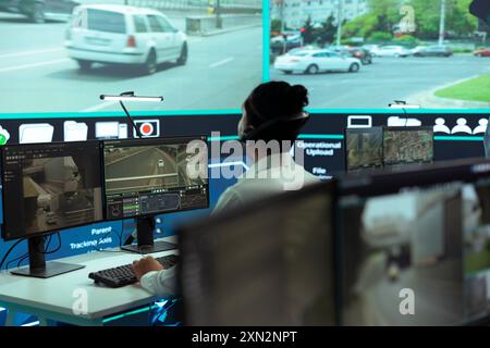 Indischer Angestellter, der Überwachungsaufnahmen auf einem Großbildschirm überwacht und den Verkehrsfluss in der Stadt überwacht. Regierungszentrale mit CCTV-Satelliten- und Radarsystem. Stockfoto