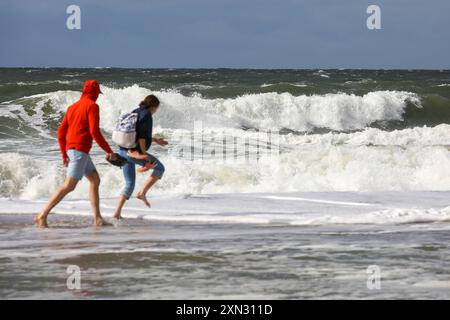 Stürmischer Spaziergang am Strand von Westerland, Sylt DEU, Deutschland, Sylt, Westerland: Das Bild zeigt zwei Personen, die barfuß am Strand von Westerland auf Sylt spazieren. Die Nordsee ist rau und stürmisch mit hohen Wellen, die gegen die Küste schlagen. Westerland Sylt Schleswig Holstein Deutschland *** Sturmwanderung am Strand von Westerland, Sylt DEU, Deutschland, Sylt, Westerland das Bild zeigt zwei Menschen, die barfuß am Strand von Westerland auf Sylt laufen die Nordsee ist rauh und stürmisch mit hohen Wellen, die gegen die Küste stürmen Westerland Sylt Schleswig Holstein Deutschland Stockfoto