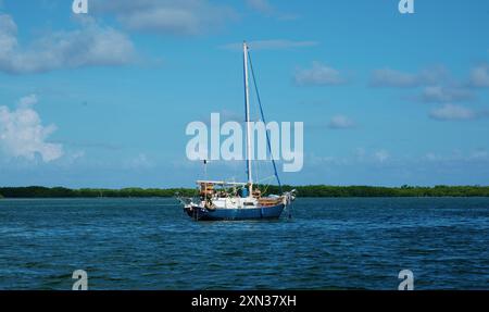 Ein einsames Segelboot, das auf ruhigem Wasser unter einem klaren blauen Himmel vor Anker liegt, perfekt für eine ruhige nautische Flucht Stockfoto