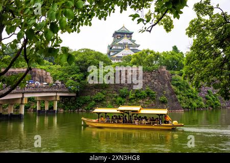 Osaka, Japan, 23. Juni 2024: Touristenfahrt auf einem gelben Boot auf dem inneren Burggraben der Burg Osaka während eines regnerischen Tages. Die Burg ist eine der berühmtesten japanischen Burgen Stockfoto