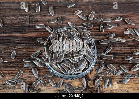 Viele Sonnenblumenkerne in Kupferschüssel. NUTS-Konzept. Blick von oben ungeschälte Sonnenblumenkerne gesalzene Sonnenblumenkerne auf altem Holz. Stockfoto