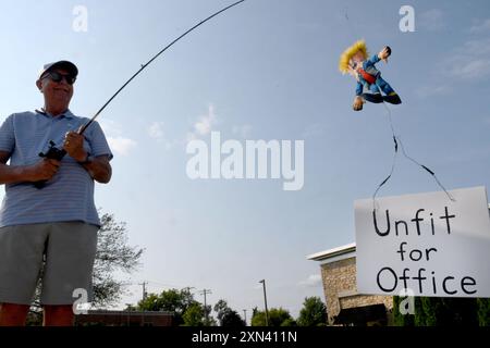 Mount Pleasant, Wisconsin, USA. 30. Juli 2024. BILL APPMAN hält eine Donald Trump Marionette am Ende einer Angelrute mit einem Schild, das Trump auf der einen Seite als „untauglich für das Amt“ und auf der anderen als „gefährliche Spezies“ bezeichnet, während er sich anderen Anti-Trump-Demonstranten an einer geschäftigen Kreuzung im Dorf Mount Pleasant, Wisconsin, anschließt. neben Racine, Dienstagnachmittag 30. Juli 2024. Er gehört zu einer Gruppe von Menschen, die seit der Amtseinführung Trumps im Jahr 2017 wöchentlich demonstriert haben. (Kreditbild: © Mark Hertzberg/ZUMA Press Wire) NUR REDAKTIONELLE VERWENDUNG! Nicht für kommerzielle ZWECKE! Stockfoto