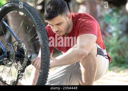 Ein junger Mann repariert das Fahrrad, ein Mann, der das Mountainbike betreut, den Umwerfer justiert Stockfoto