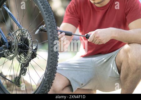 Ein Mann pumpt einen Fahrradreifen mit einer kleinen Handpumpe, ein junger Mann, der einen Fahrradreifen mit einer kleinen Pumpe in der Nähe aufbläst Stockfoto