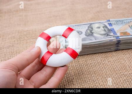 Rettungsring in der Hand über die Banknote Bündel von US-dollar Stockfoto