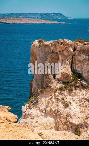 Atemberaubender Blick auf eine Küstenlandschaft mit zerklüfteten felsigen Klippen und einem klaren blauen Meer unter hellem Himmel. Stockfoto