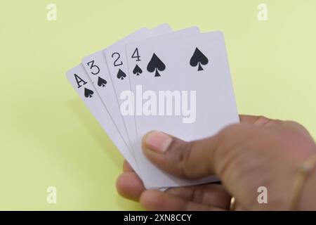 Eine Hand mit Spielkarten zeigt eine gewinnende Pokerhand - ein geradliniger Spatenschlag. Stockfoto