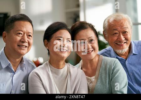 Eine Gruppe glücklicher älterer asiatischer Leute, die zu Hause auf der Couch sitzen und gemeinsam fernsehen Stockfoto