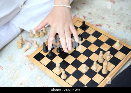 Mädchen, das Schach spielt, sitzt auf dem Boden bewegte Stücke - Konzept Denken Fähigkeiten Entscheidungsstrategie Nächster Schritt Stockfoto
