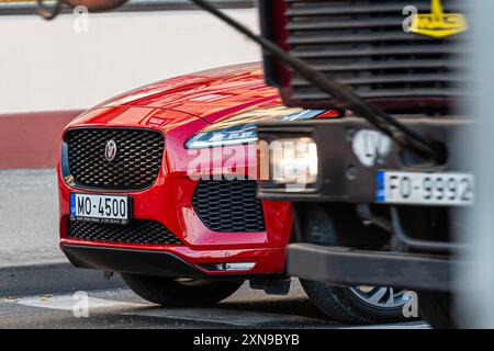 Riga, Lettland - 30. September 2020: Ein hellrotes Auto parkt in der Nähe eines großen Lastwagens und wird im Nachmittagslicht gefangen. Stockfoto