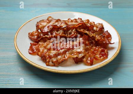 Scheiben leckeren gebratenen Speck auf hellblauem Holztisch Stockfoto