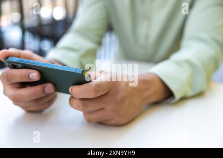 Nicht erkennbarer Mann, der ein Mobiltelefon benutzt, um Videospiele im Freien zu spielen Stockfoto