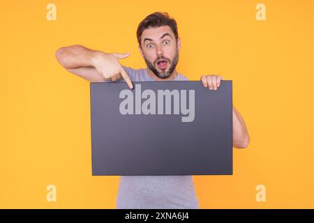 Der Mann hält ein Schild mit Kopierraum. Plakat bereit für Kopiergerät. Signieren Sie in den Text im Kopierbereich. Ein Mann mit leerem Schild im Studiohintergrund Stockfoto