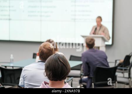 Die Teilnehmer waren mit einem Referenten beschäftigt, der auf einer Geschäftskonferenz oder einem Seminar in einer modernen Büroumgebung vorstellte Stockfoto