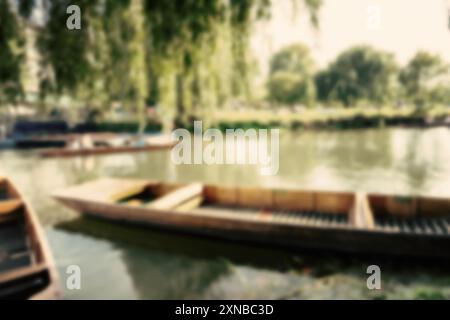 Ein verschwommenes Bild eines Holzbootes auf einem ruhigen Fluss in Cambridge, Großbritannien. Das Boot ist teilweise im Wasser untergetaucht und scheint sich mit dem zu bewegen Stockfoto