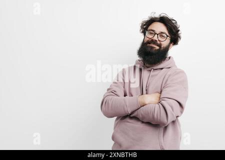 Lächelnder bärtiger Mann in einem Hoodie, der selbstbewusst posiert Stockfoto