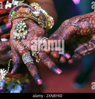 Zärtliche Hände einer indischen Braut, bedeckt mit Henna-Tattoo, halten die Hand des Bräutigams, Ringzeremonie. Stockfoto