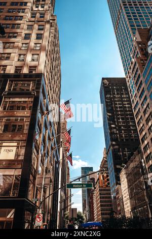 Hohe moderne Gebäude mit amerikanischen Flaggen in der Innenstadt von New York, Manhattan vor blauem Himmel Stockfoto