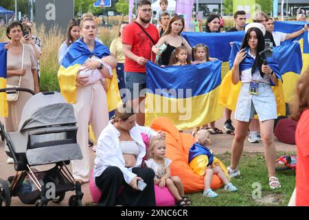 KIEW, UKRAINE - 26. JULI 2024 - Menschen mit ukrainischer Flagge nehmen an einer Veranstaltung zur Eröffnungszeremonie der Olympischen Sommerspiele 2024 in Paris in der Fanzone auf dem Expocenter der Ukraine (VDNG) in Kiew, Hauptstadt der Ukraine, Teil. Stockfoto