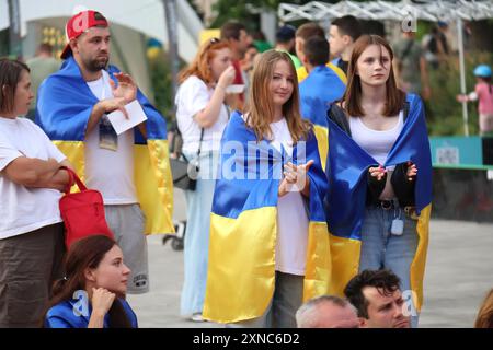 KIEW, UKRAINE - 26. JULI 2024 - Menschen mit ukrainischer Flagge nehmen an einer Veranstaltung zur Eröffnungszeremonie der Olympischen Sommerspiele 2024 in Paris in der Fanzone auf dem Expocenter der Ukraine (VDNG) in Kiew, Hauptstadt der Ukraine, Teil. Stockfoto