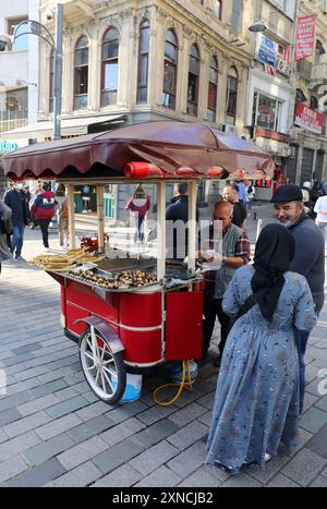 ISTANBUL, TÜRKEI-08. NOVEMBER 2021: Unbekannte Kunden, die Kastanien von einem Anbieter in der Istiklal Avenue kaufen Stockfoto