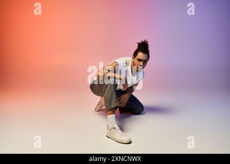 Ein junger afroamerikanischer Tänzer posiert in dynamischer Position vor einem leuchtenden rosa und violetten Farbverlauf. Stockfoto