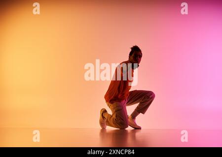 Ein junger afroamerikanischer Tänzer posiert in einem Studio-Setting vor einem farbenfrohen Hintergrund. Stockfoto