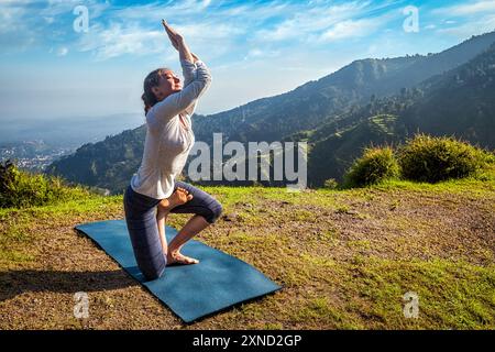 Junge Frau, die Ashtanga Vinyasa Yoga machte, entwickelte schwierige Asana Vatayanasana (Pferdehaltung) im Freien in Himalaya-Bergen. Himachal Pradesh, Indien Stockfoto